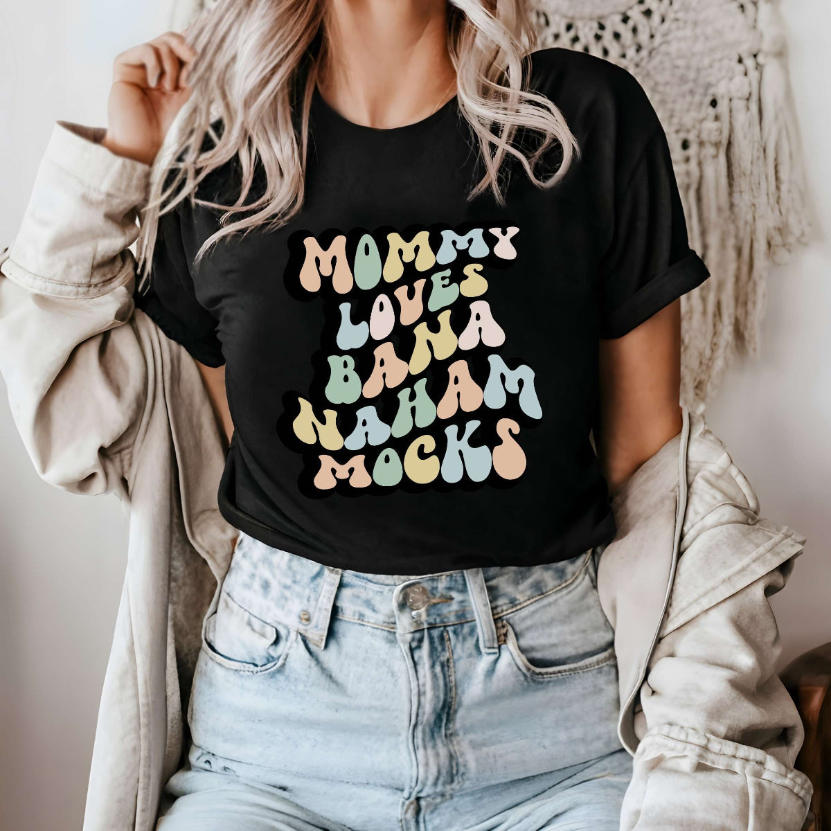 Graphic tee for women. The color of the shirt is black. In a colorful, typically 70s retro-style font it says Mommy Loves Banana Hammocks.