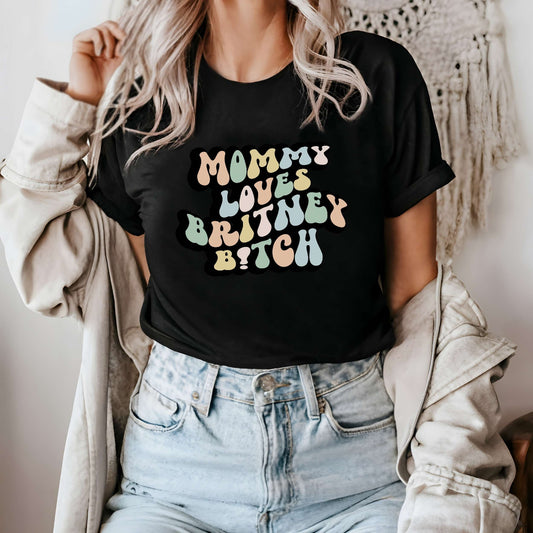 Graphic tee for women. The color of the shirt is black. In a colorful, typically 70s retro-style font it says Mommy Loves Britney B*tch.