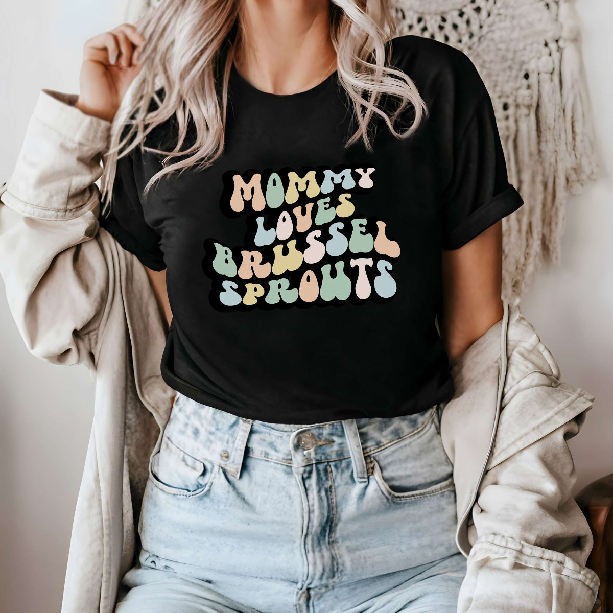Graphic tee for women. The color of the shirt is black. In a colorful, typically 70s retro-style font it says Mommy Loves Brussel Sprouts.