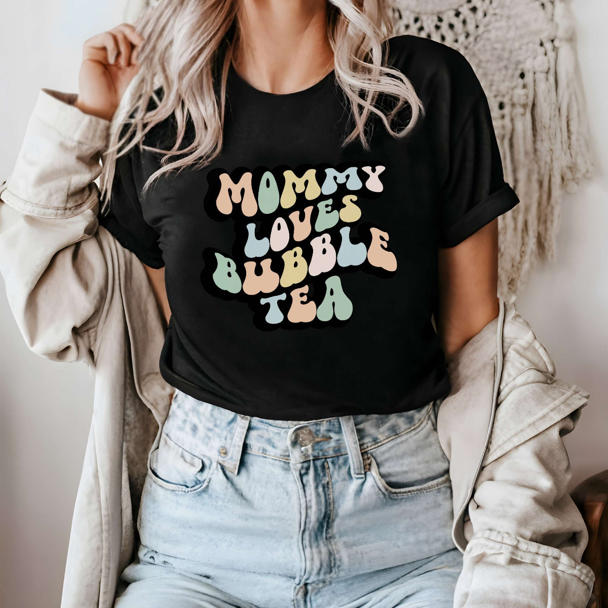 Graphic tee for women. The color of the shirt is black. In a colorful, typically 70s retro-style font it says Mommy Loves Bubble Tea.