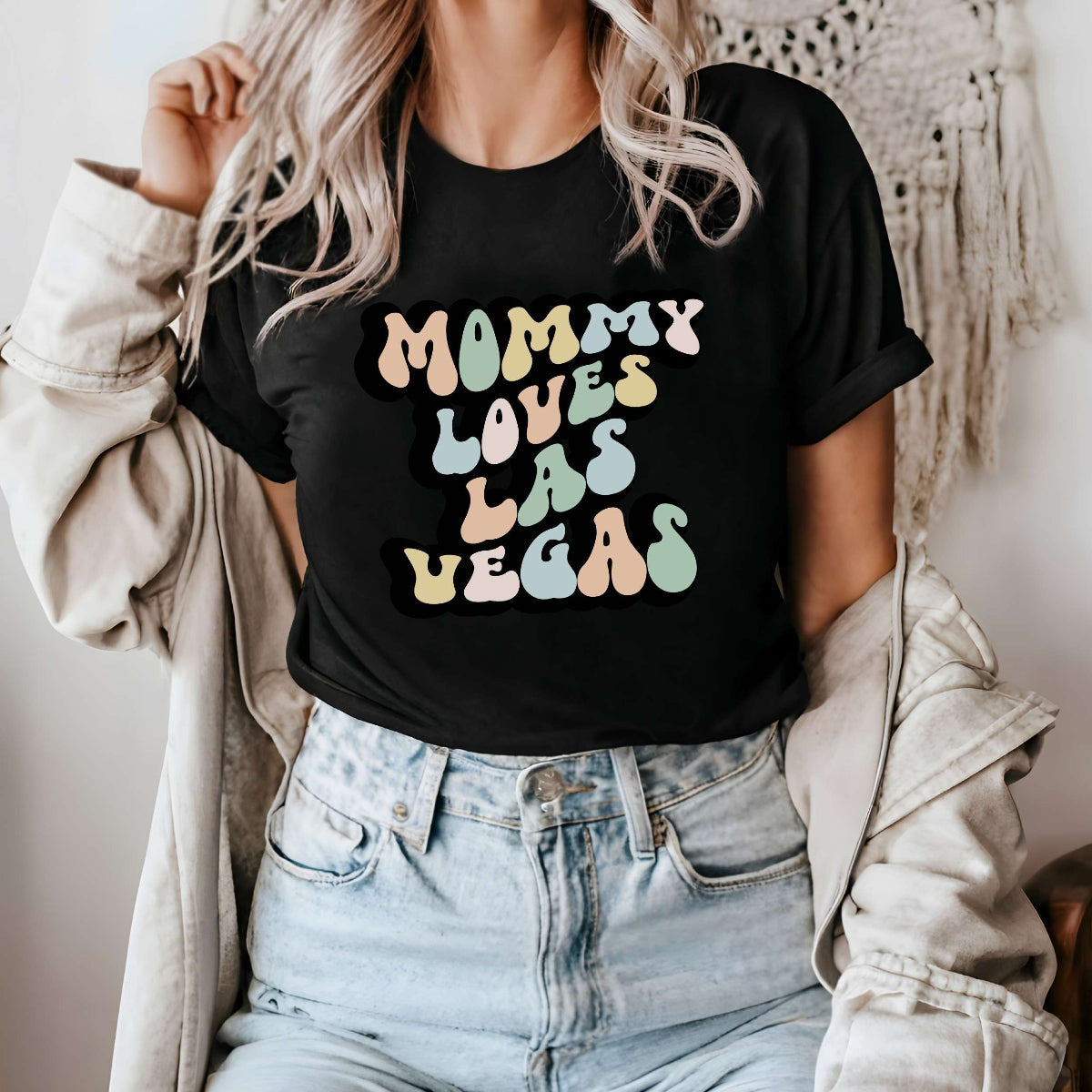 Graphic tee for women. The color of the shirt is black. In a colorful, typically 70s retro-style font it says Mommy Loves Las Vegas.