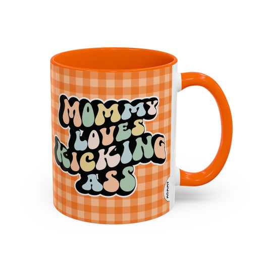 Perfect gift for mom. A decorative, 11oz ceramic mug. It’s wrapped in a orange-white checkered background. In a happy and colorful 70s retro-style font it says Mommy Loves Kicking Ass on both sides.