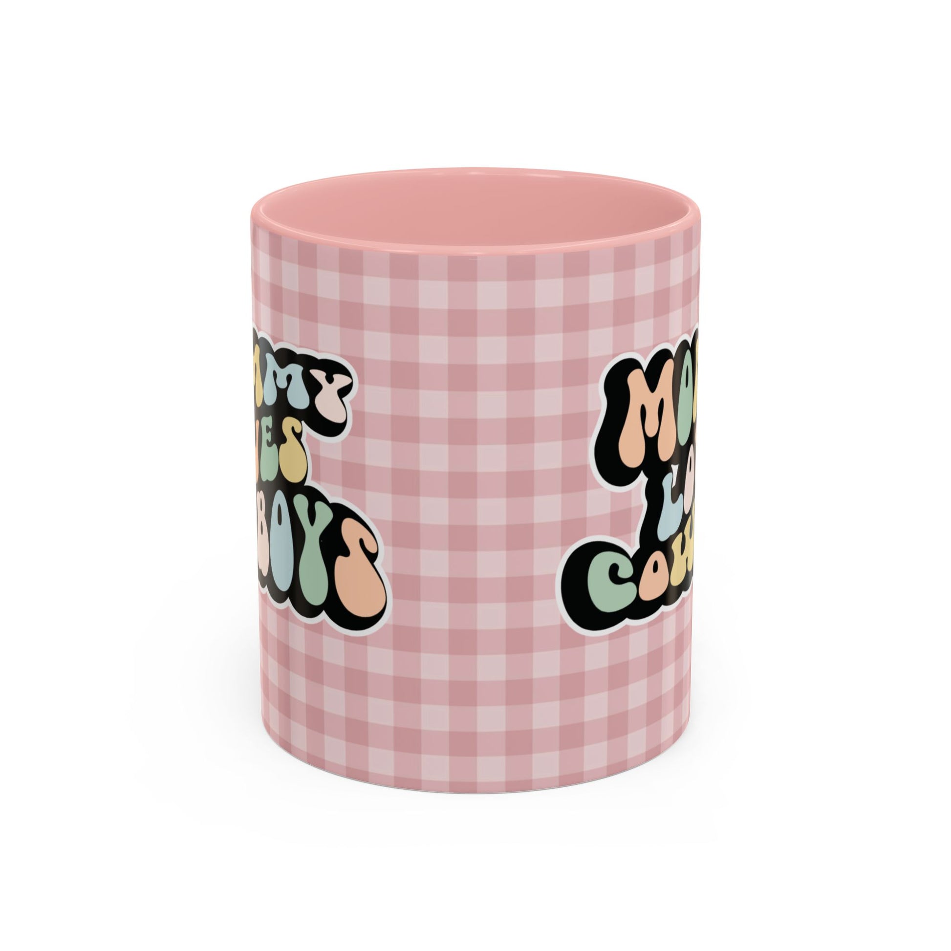 Perfect gift for mom. A decorative, 11oz ceramic mug. It’s wrapped in a soft pink-white checkered background. In a happy and colorful 70s retro-style font it says Mommy Loves Cowboys, on both sides.