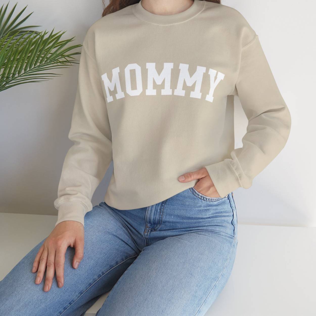 Perfect gift for Mom. Our mother's day special. The model is wearing our crewneck sweatshirt in sand color. On the chest it says MOMMY in big white varsity lettes.