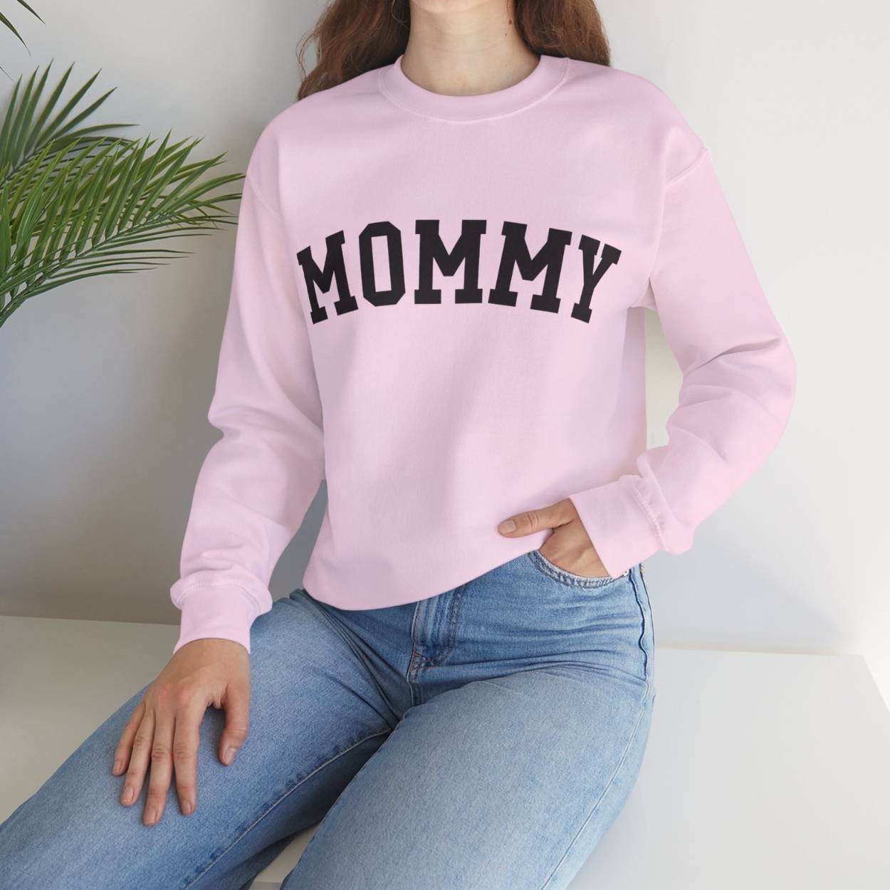 The perfect gift for mom. Our Mother’s Day special. Our crewneck sweatshirt. The color of the shirt is light pink, and in big black varsity letters it says MOMMY on the chest. It’s available in six sizes, ranging from S to 3XL.