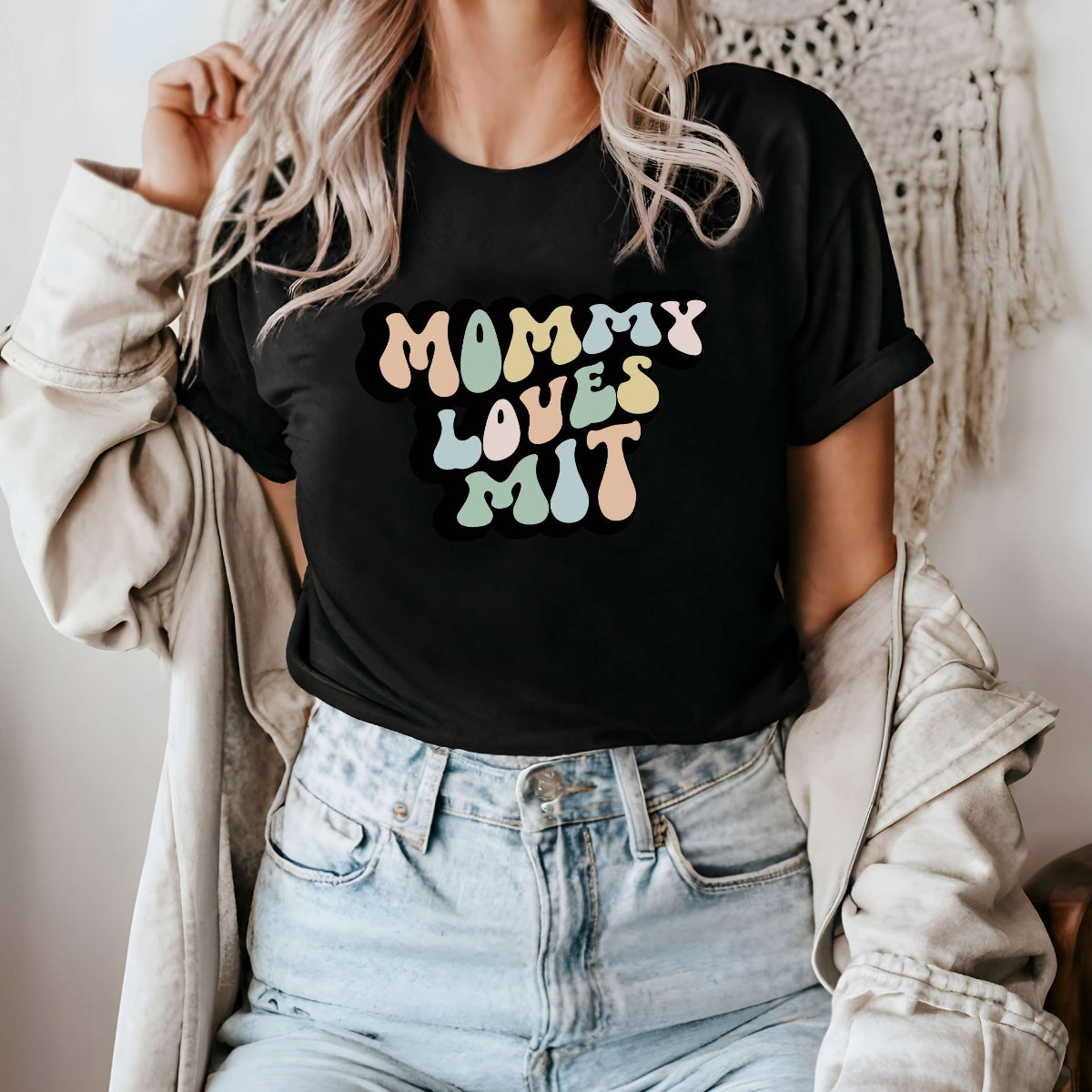 Graphic tee for women. The color of the shirt is black. In a colorful, typically 70s retro-style font it says Mommy Loves MIT.