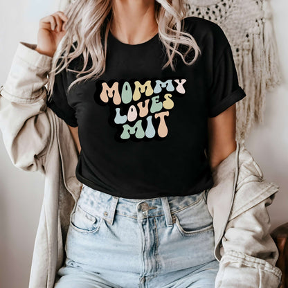 Graphic tee for women. The color of the shirt is black. In a colorful, typically 70s retro-style font it says Mommy Loves MIT.