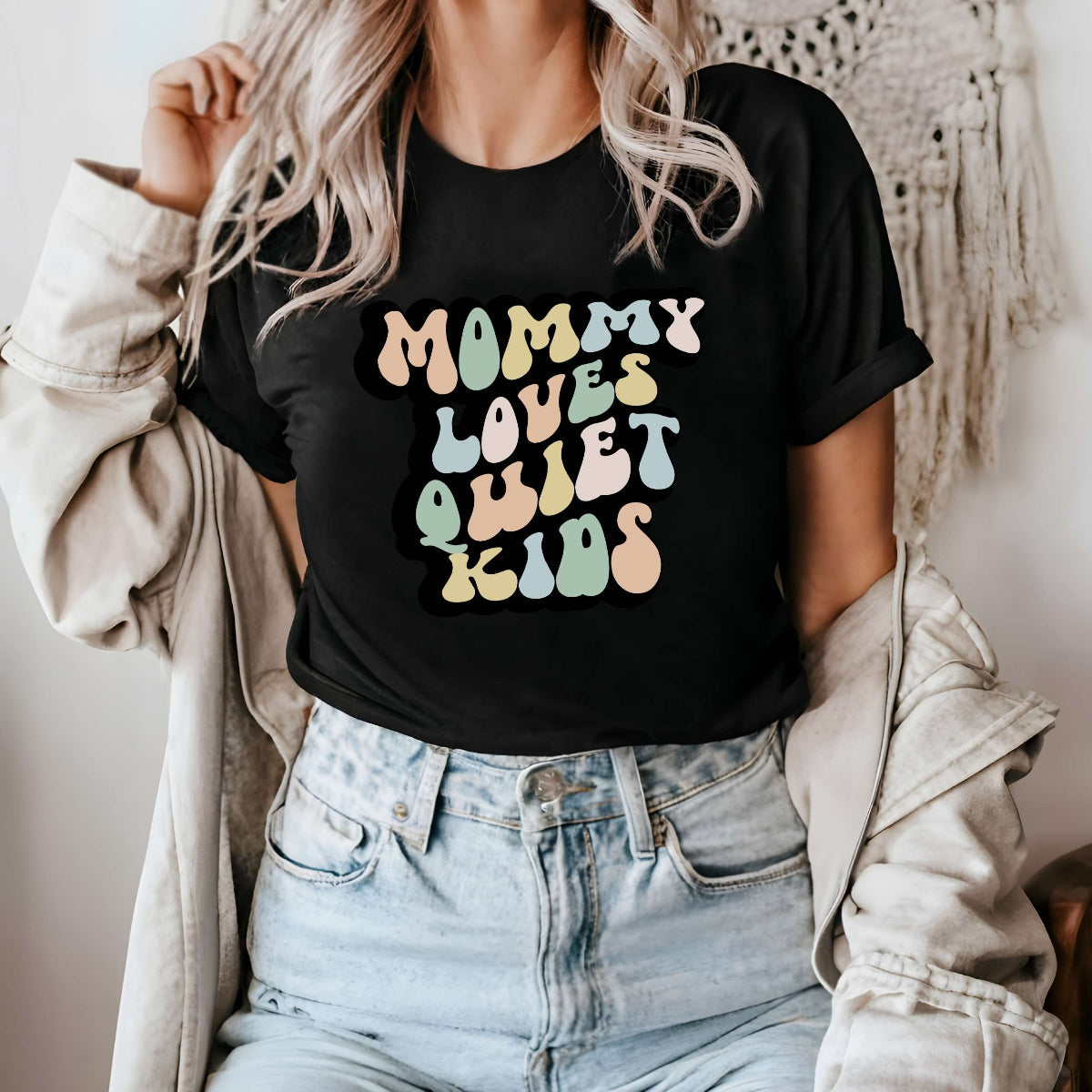 Graphic tee for women. The color of the shirt is black. In a colorful, typically 70s retro-style font it says Mommy Loves Quiet Kids.