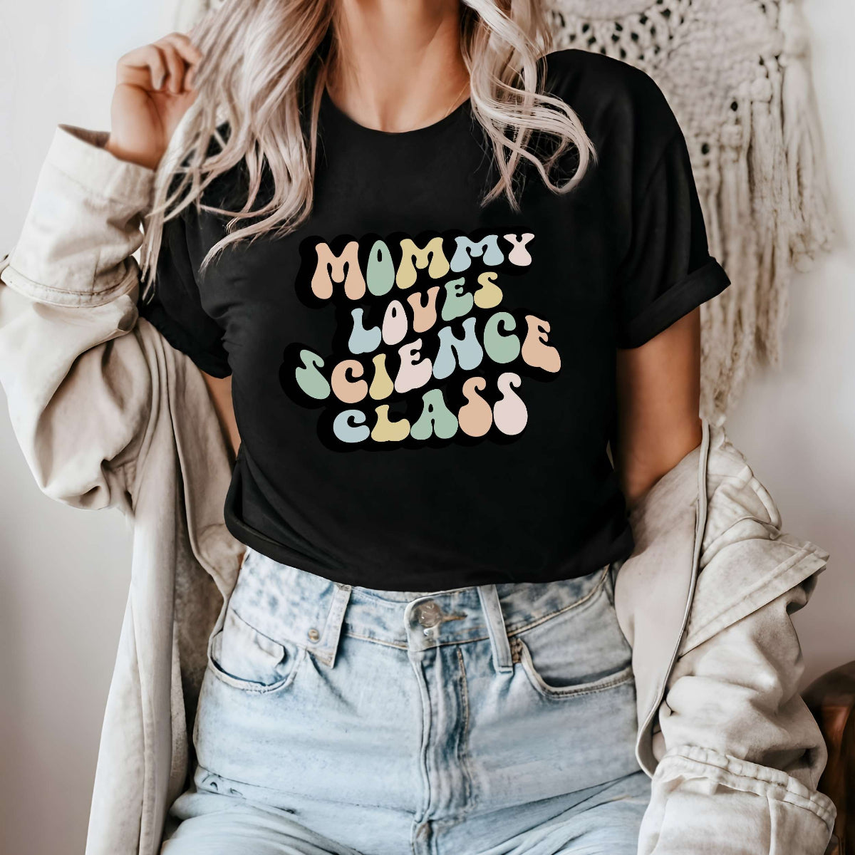 Graphic tee for women. The color of the shirt is black. In a colorful, typically 70s retro-style font it says Mommy Loves Science Class.