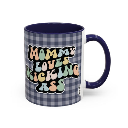 Perfect gift for mom. A decorative, 11oz ceramic mug. It’s wrapped in a navy blue-white checkered background. In a happy and colorful 70s retro-style font it says Mommy Loves Kicking Ass on both sides. 