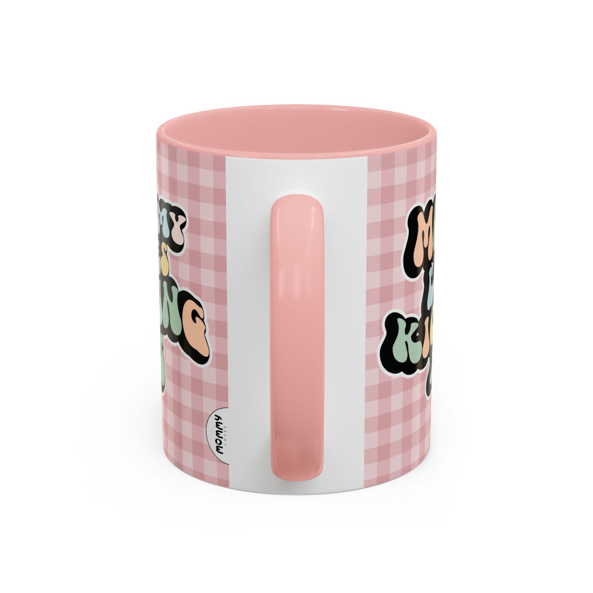 Perfect gift for mom. A decorative, 11oz ceramic mug. It’s wrapped in a soft pink-white checkered background. In a happy and colorful 70s retro-style font it says Mommy Loves Kicking Ass on both sides. 