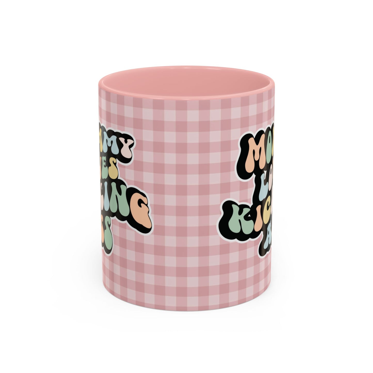 Perfect gift for mom. A decorative, 11oz ceramic mug. It’s wrapped in a soft pink-white checkered background. In a happy and colorful 70s retro-style font it says Mommy Loves Kicking Ass on both sides. 