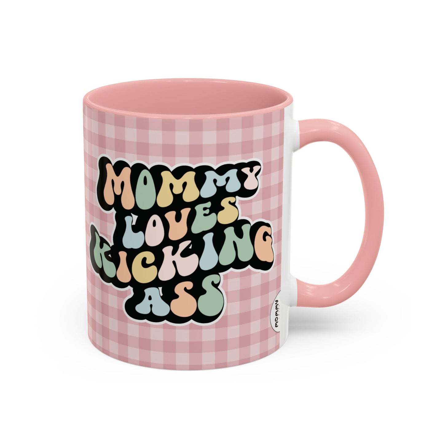 Perfect gift for mom. A decorative, 11oz ceramic mug. It’s wrapped in a soft pink-white checkered background. In a happy and colorful 70s retro-style font it says Mommy Loves Kicking Ass on both sides. 