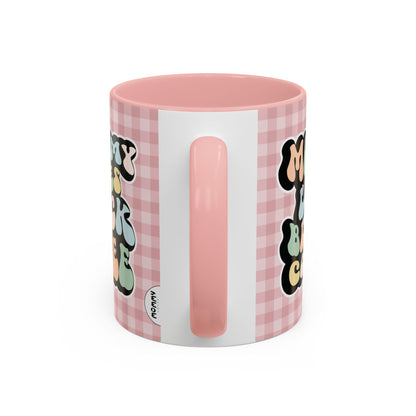 Perfect gift for mom. A decorative, 11oz ceramic mug. It’s wrapped in a soft pink-white checkered background. In a happy and colorful 70s retro-style font it says Mommy Loves Black Coffee on both sides. 
