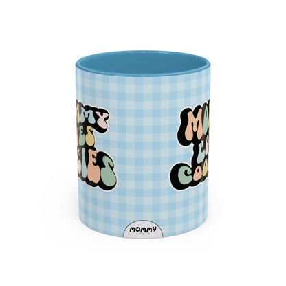 Perfect gift for mom. A decorative, 11oz ceramic mug. It’s wrapped in a light blue-white checkered background. In a happy and colorful 70s retro-style font it says Mommy Loves Cookies, on both sides. 