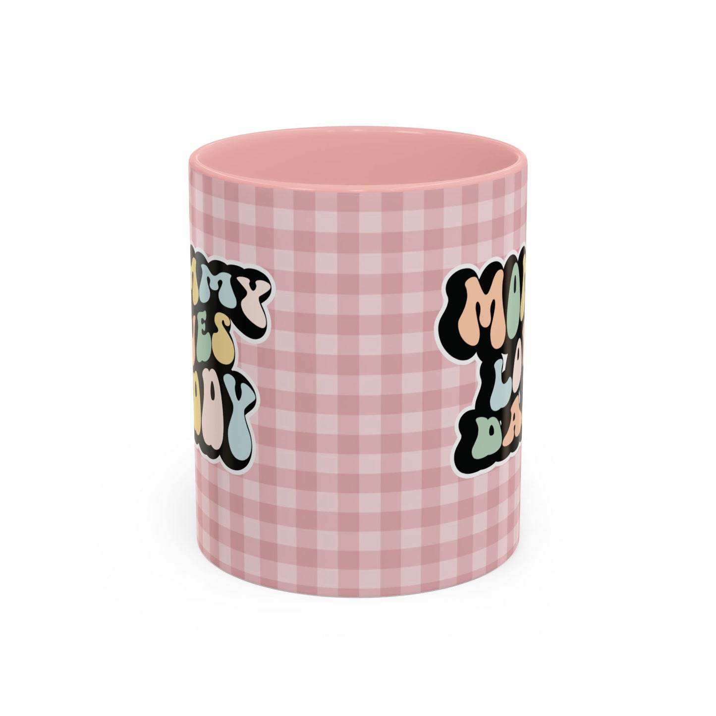 Perfect gift for mom. A decorative, 11oz ceramic mug. It’s wrapped in a soft pink-white checkered background. In a happy and colorful 70s retro-style font it says Mommy Loves Daddy, on both sides. 