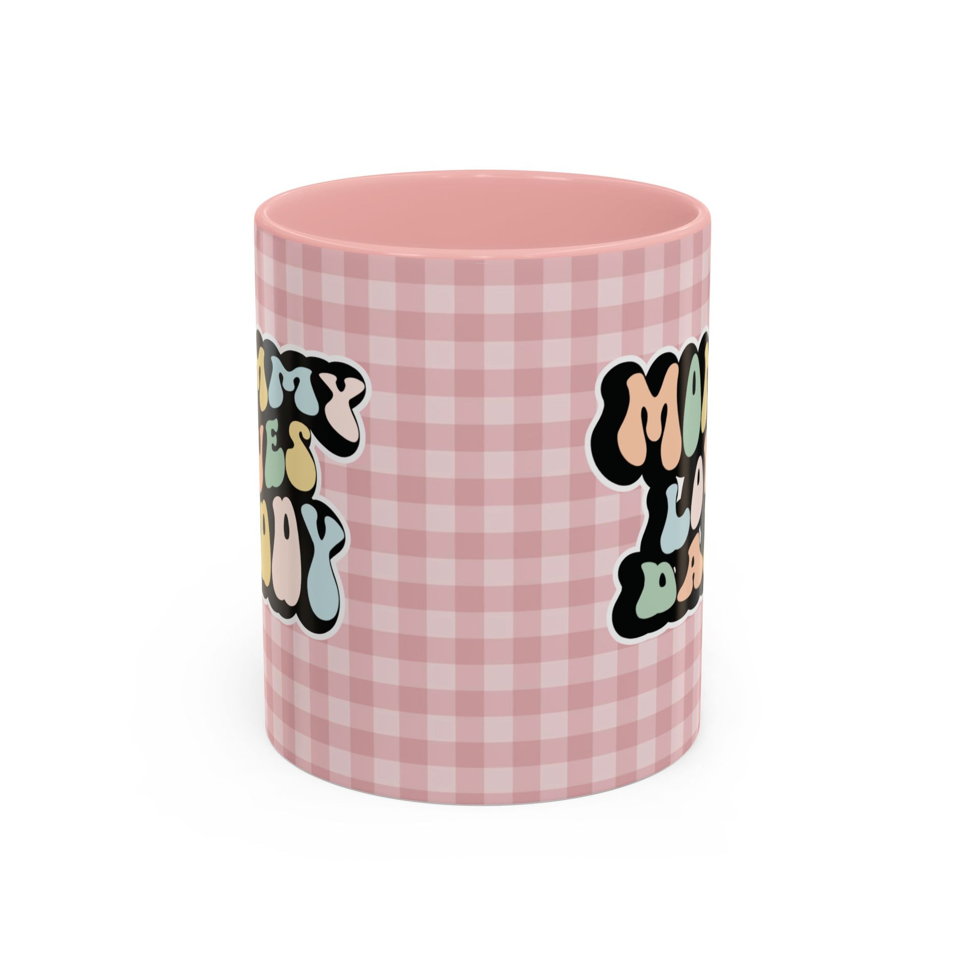 Perfect gift for mom. A decorative, 11oz ceramic mug. It’s wrapped in a soft pink-white checkered background. In a happy and colorful 70s retro-style font it says Mommy Loves Daddy, on both sides. 