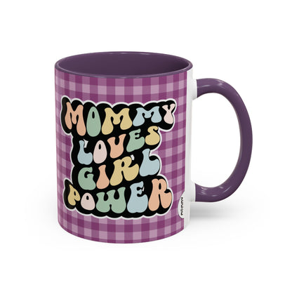 Perfect gift for mom. A decorative, 11oz ceramic mug. It’s wrapped in a purple-white checkered background. In a happy and colorful 70s retro-style font it says Mommy Loves Girl Power, on both sides. 