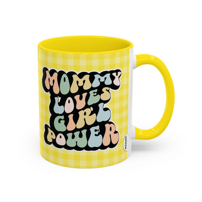 Perfect gift for mom. A decorative, 11oz ceramic mug. It’s wrapped in a yellow-white checkered background. In a happy and colorful 70s retro-style font it says Mommy Loves Girl Power, on both sides. 