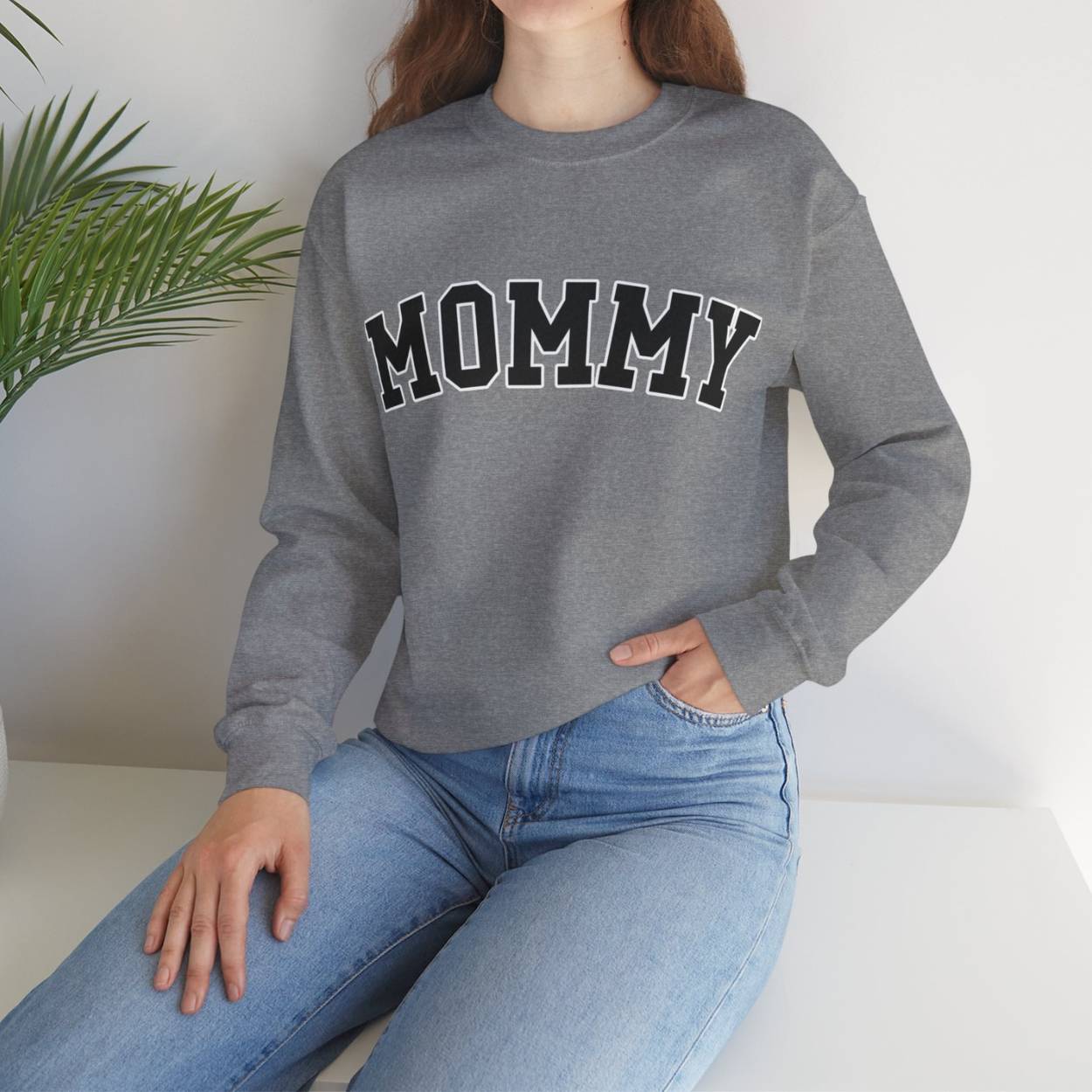 The perfect gift for mom. Our Mother’s Day special. The model in the picture is wearing our crewneck sweatshirt. The color of the shirt is sport grey, and in big varsity letters it says MOMMY on the chest. It’s available in six sizes, ranging from S to 3XL. 