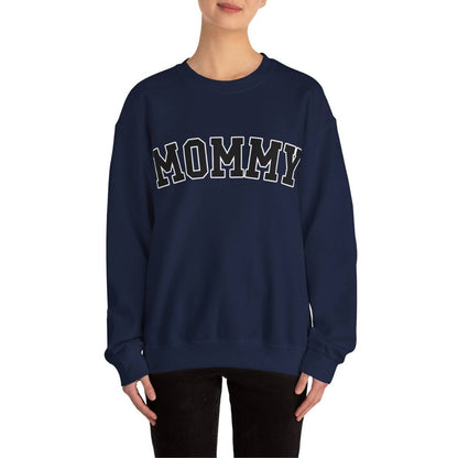 The perfect gift for mom. Our Mother’s Day special. The model is wearing our crewneck sweatshirt. The color of the shirt is navy blue, and in big varsity letters it says MOMMY on the chest. It’s available in six sizes, ranging from S to 3XL. 