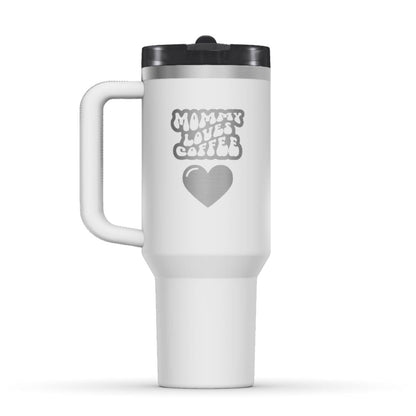 Stanley 40oz Tumbler, with a personalized twist. The perfect gift for mom. The Color of the cup is chalk, a shade of white. It’s engraved with a typically 70s retro-style font, saying Mommy Loves Coffee. Under that text there is a nice big heart in the same style. 
