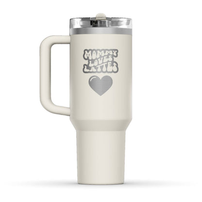 The back side of the newest Stanley 40oz Tumbler. The perfect gift for mom. The Color of the cup is Cream, a shade of off-white. It’s engraved with a typically 70s retro-style font, saying Mommy Loves Lattes. Under that text there is a nice big heart in the same retro style.