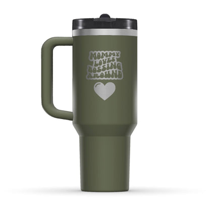 The back side of the newest Stanley 40oz Tumbler. The perfect gift for mom. The Color of the cup is Dried Pine, a dark shade of army green. It’s engraved with a typically 70s retro-style font, saying Mommy Loves Bossing Around. Under that text there is a nice big heart in the same retro style.
