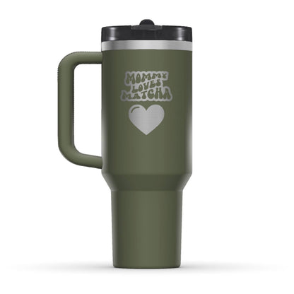 The back side of the newest Stanley 40oz Tumbler. The perfect gift for mother’s day. The Color of the cup is Dried Pine, which is a dark shade of army green. It’s engraved with a typically 70s retro-style font, saying Mommy Loves Matcha. Under that text there is a nice big heart in the same retro style.