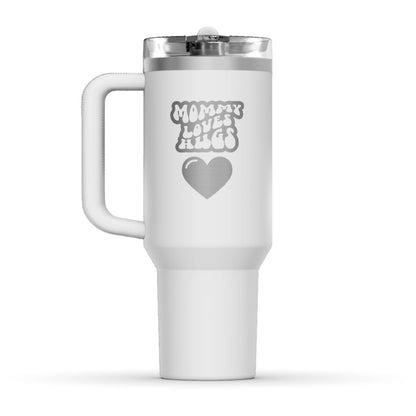 The back side of the newest Stanley 40oz Tumbler. The perfect gift for mom. The Color of the cup is Frost, a shade of fresh white. It’s engraved with a typically 70s retro-style font, saying Mommy Loves Hugs. Under that text there is a nice big heart in the same retro style.