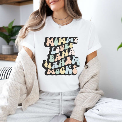Graphic tee for women. The color of the shirt is white. In a colorful, typically 70s retro-style font it says Mommy Loves Banana Hammocks.